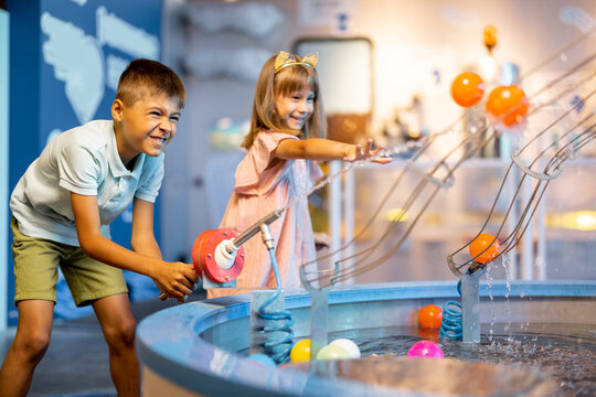 Little boy and girl play with balls, learning physical phenomena in an interesting way, having fun in a science museum with interactive models