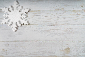 Fototapeta premium One snowflake on a white wooden background. Christmas winter flatlay with copyspace
