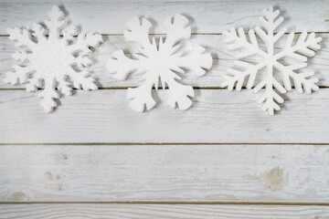 Three snowflakes on a white wooden background. Christmas winter flatlay with copyspace