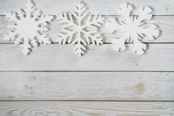 Three snowflakes on a white wooden background. Christmas winter flatlay with copyspace