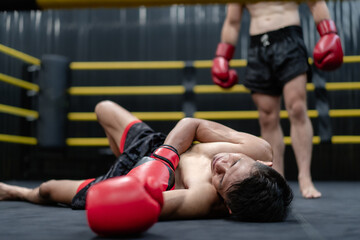 Unconscious Asian boxer lay on floor referee countdown knockout in fighting ring at fitness gym....