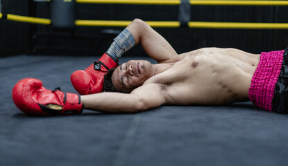 Unconscious Asian boxer lay on floor referee countdown knockout in fighting ring at fitness gym....