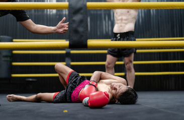 Unconscious Asian boxer lay on floor referee countdown knockout in fighting ring at fitness gym....