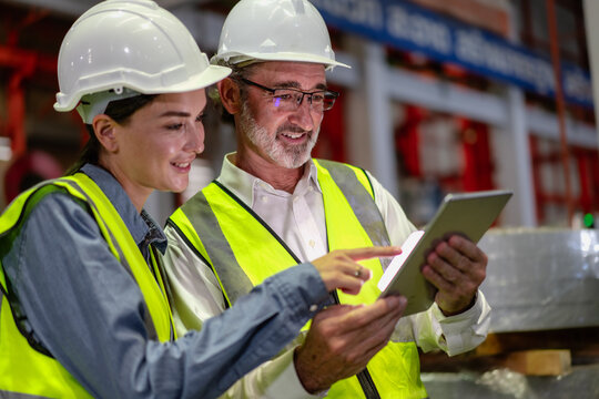 Senior manager train female technician working in metalwork production factory. Industrial engineer teamwork standing in manufacturing facility talking machinery maintenance in heavy steel industry. - Powered by Adobe