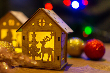 New Year's wooden house and Santa Claus against the background of Christmas decorations and bright colored bokeh