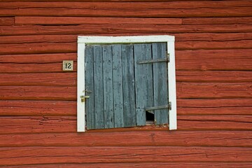 Weathered white framed black door on red wooden building.