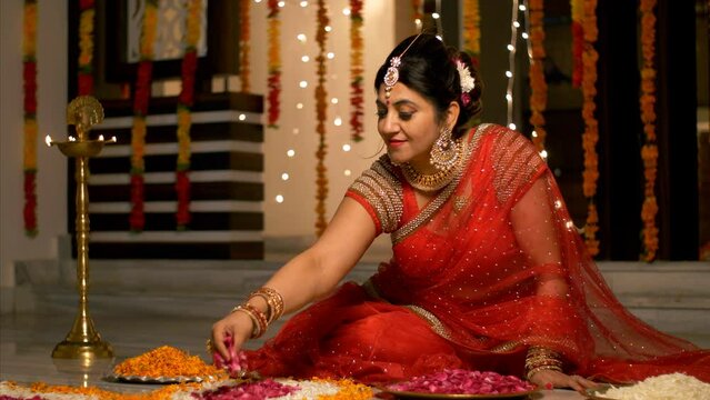 Diwali Festival - Traditional Indian house wife in red saree making flower rangoli. 