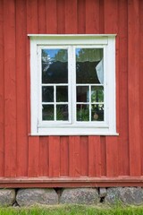 White framed window on a red wood building.