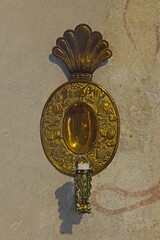 Closeup of a metal candle holder on a stone wall.