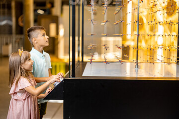 Little boy and girl studying physics and magnetic field on an interactive model in the science museum. Concept of children's entertainment and learning