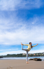 Woman doing ballerina yoga pose on the beach