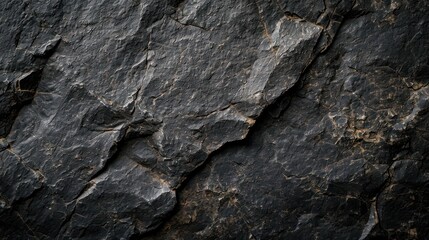 A textured black stone background crafted from the rough, dark grey surface of a mountain, complete with cracks and ample space for creative design