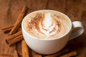 Foto op Plexiglas coffee composition. a cup of cappuccino with foam and a pattern of a tree leaf, cinnamon pods lie nearby, creative concept © ibragimova