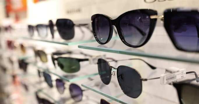 Stylish trendy sunglasses on shelf in store. Selection of quality sunglasses