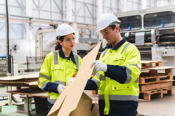 Professional worker team in safety uniform, supervisor inspector in packaging stock order at cardboard factory warehouse, piles of stacking paper manufacture, recycling industrial production