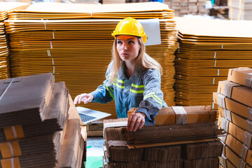 Fototapeta premium Professional worker team in safety uniform, supervisor inspector in packaging stock order at cardboard factory warehouse, piles of stacking paper manufacture, recycling industrial production