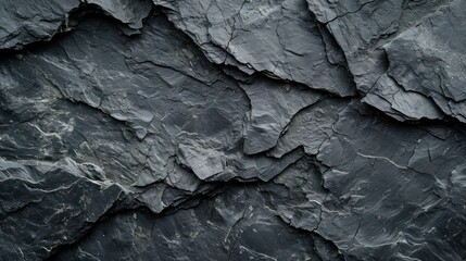 Textured black stone background created by a dark grey, rugged mountain surface with prominent cracks. Designers have plenty of space for creativity.
