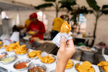 Hand Holding Traditional Latin Empanada at Street Food Stall