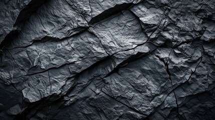 A textured black stone background crafted from the rough, dark grey surface of a mountain, complete with cracks and ample space for creative design.