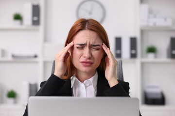 Woman suffering from headache at workplace in office