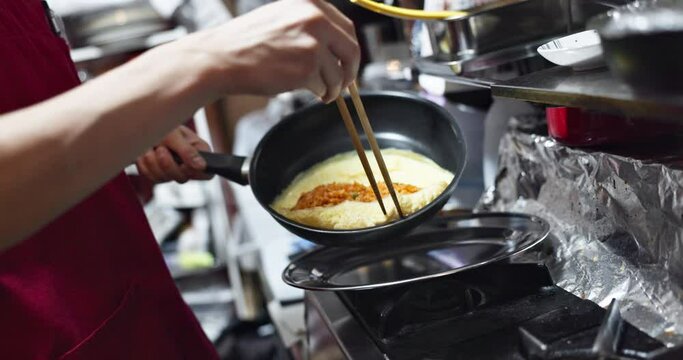 Hands, food or omelette in kitchen with chef for Japanese lunch, dinner or healthy meal for nutrition. Person, omurice and preparation or cooking with chopsticks in restaurant, cafe or small business