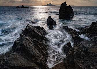 Obraz premium 夕暮れの海で岩場に打ち寄せる波