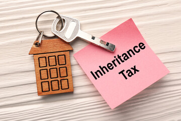 Inheritance Tax. Paper note and key with key chain in shape of house on white wooden table, flat lay