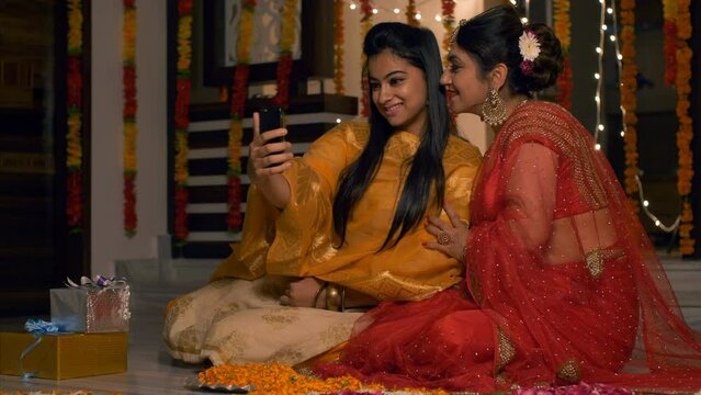 Indian mother and daughter taking a picture - Diwali  Indian festival  smartphone  selfie  festive vibes  Onam  Vaisakhi . Women in traditional clothes celebrating Deepawali - vibrant garments  bri...
