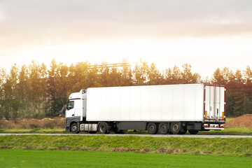 Commercial vehicles for shipping and post delivery drive on a motorway. White trucks with semi trailers carrying cargo containers. Sustainable and efficient logistics practices to transport goods.