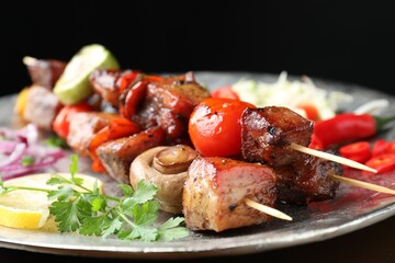Delicious shish kebabs with vegetables on black background, closeup