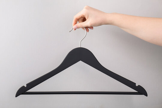 Woman holding hanger on light grey background, closeup