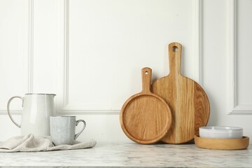 Wooden cutting boards, dishware and towel on white marble table