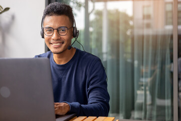 close up call center indian man wear headset and smiling while working in office with service-mind...