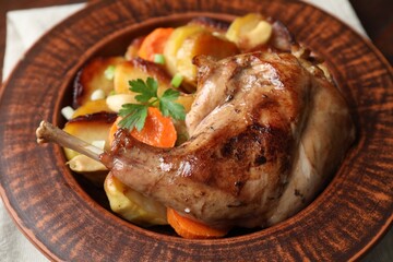 Tasty cooked rabbit meat with vegetables on table, closeup