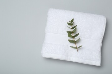 White terry towel and eucalyptus branch on light grey background, top view. Space for text