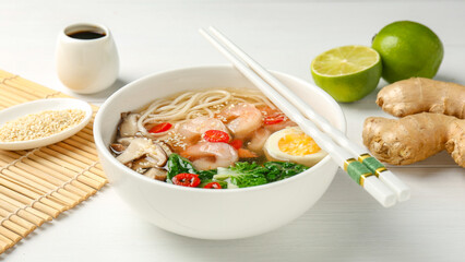 Tasty ramen with shrimps in bowl and chopsticks on white table