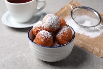Delicious sweet buns in bowl, cup of drink and strainer on gray table