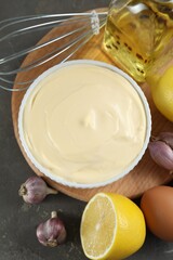 Fresh mayonnaise sauce in bowl and ingredients on grey table, flat lay