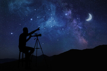 Astronomer with telescope pointing at starry sky outdoors