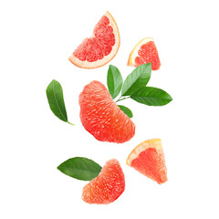 Fresh grapefruit pieces and green leaves falling on white background