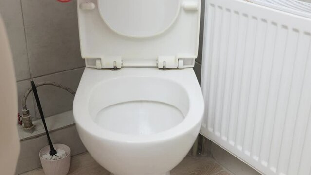 Unrecognizable woman wearing gloves cleaning and disinfecting toilette in home bathroom doing her housekeeping routine washing bathroom