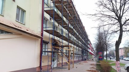 Scaffolding along an old multi-storey building in the city. Reconstruction and repair of window frames, facades, production of new balconies, industry