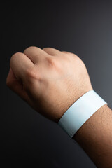 Blue paper wristband mockup on persons arm. Empty adhesive bangle wristlet sticker on male hand,...