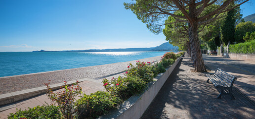 lakeside promenade Maderno, lake Gardasee, with bench and roses, italy tourist resort