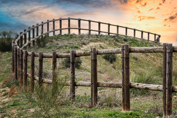 Wooden fence in an agricultural field with sunset in the background.