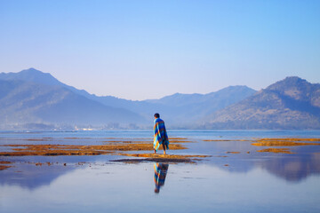 person standing on the lake with blue hour mountain background