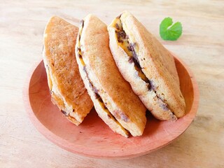 pieces of martabak filled with chocolate sprinkles on a wooden plate on a white background. martabak, traditional Indonesian sweet snack. soft bread filled with chocolate, for tea time or celebrition