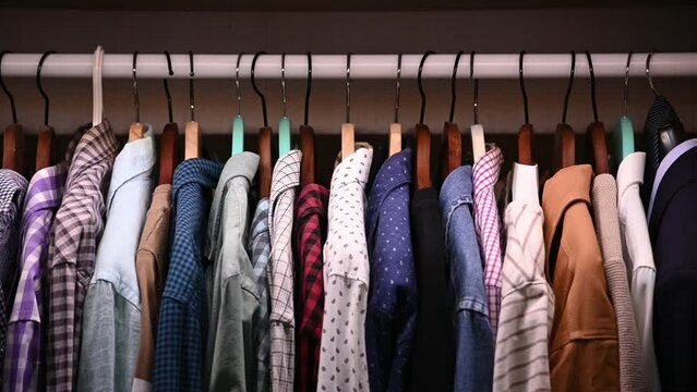 Opening closet doors. Hangers inside male wardrobe with many shirts and jackets