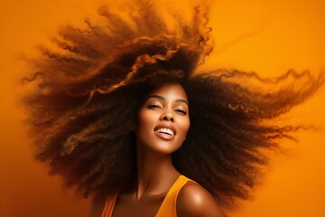 closeup of beautiful black african american young female model woman shaking her beautiful afro hair in motion. ad for shampoo conditioner hair products. isolated on orange background - obrazy, fototapety, plakaty