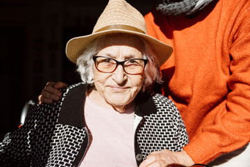 Portrati of a smiling ninety three years old woman with a straw hat under the sunlight. - obrazy, fototapety, plakaty